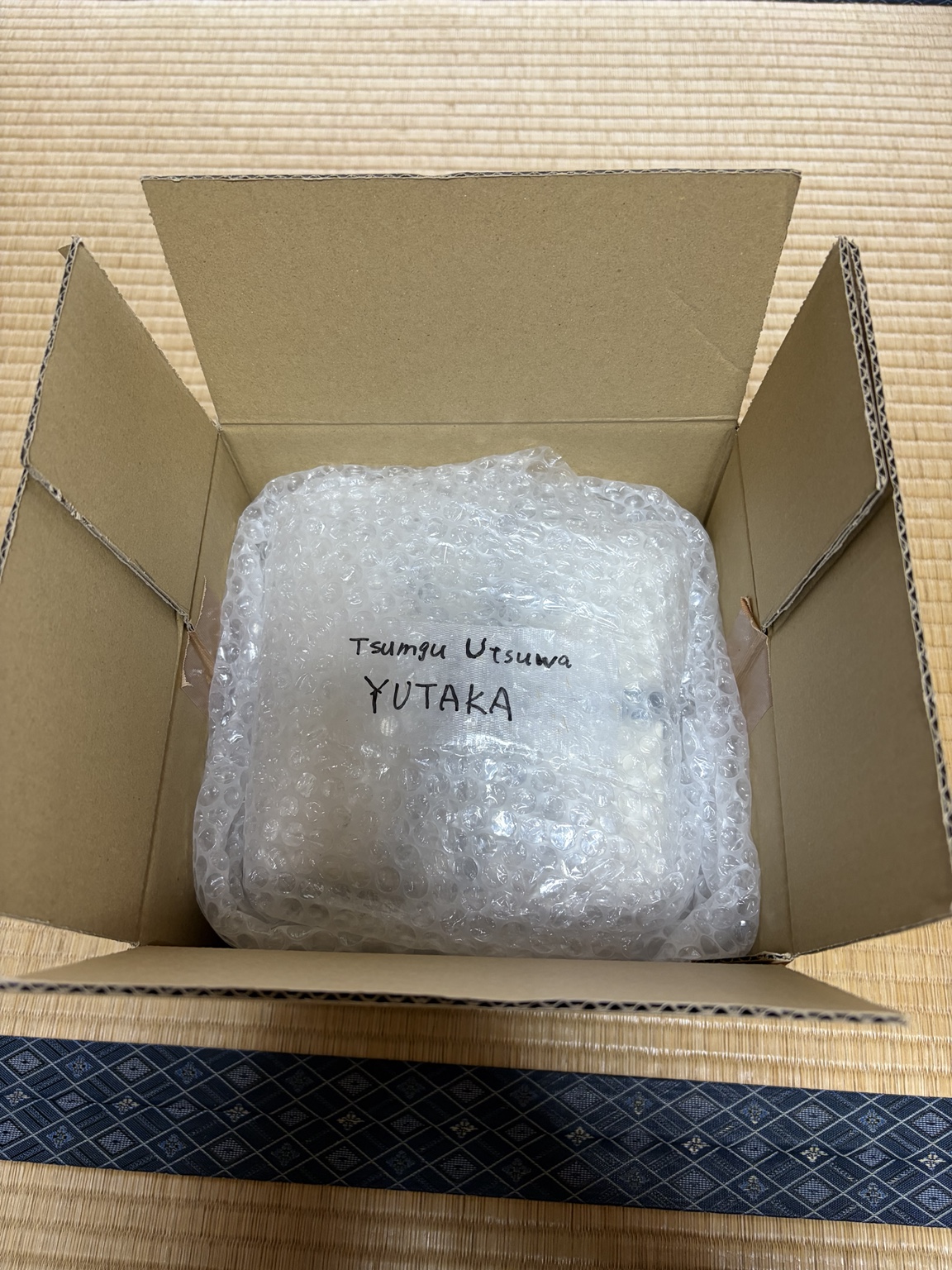 つむぐうつわと書かれた包みが箱に収められ、参加者へ届けられる様子
